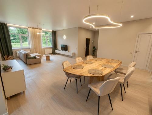 a living room with a wooden table and chairs at Lapsiņmuiža Pool House - Pool, Sauna & Hot-tub included in Dzedri