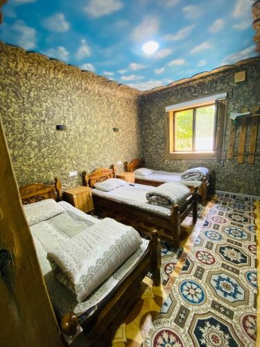 a room with three beds and a window and a rug at Ikhtiyor guest house with mountainiring hiking horse riding serivices in Yukary-Ukhum