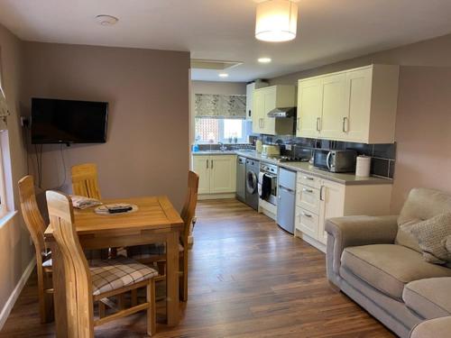 a living room with a table and a kitchen at Rose cottage in Wellington