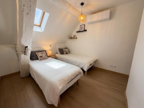 two beds in a small room with a window at La Suite Celeste in Nuits-Saint-Georges