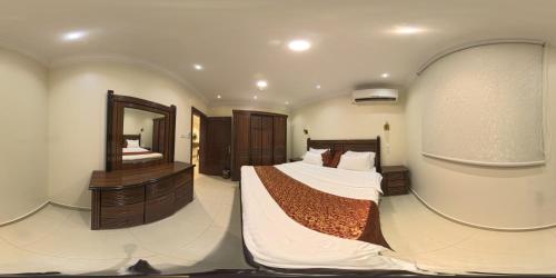 a bedroom with a large bed and a mirror at شقق ابراهيم ناصر الضاوي للشقق المخدومة in Al Majma'ah