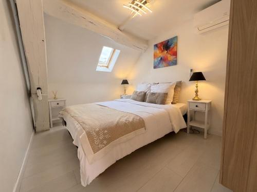 a white bedroom with a large bed and two night stands at La Suite Celeste in Nuits-Saint-Georges