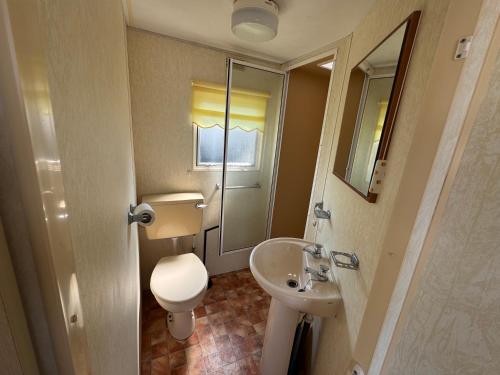 a small bathroom with a toilet and a sink at Sweet Caravan - Hemsby in Hemsby