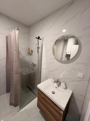 ein Badezimmer mit Waschbecken, Dusche und Spiegel in der Unterkunft Apartment EDA in Bosanska Krupa