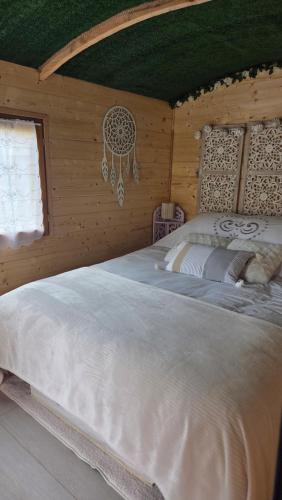 a bedroom with a white bed in a wooden room at Un aparté bohême "La Roubane" in Puyravault