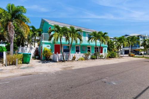 a blue house with palm trees in front of a street at Bay View Inn 202 in Bradenton Beach