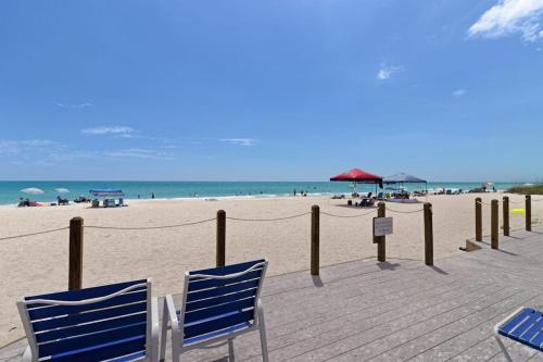 two blue chairs sitting on a boardwalk on the beach at Gulf Place 19 in Holmes Beach