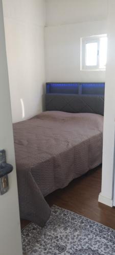 a bedroom with a bed with a blue headboard and a window at L'évidence in Alcantarilha