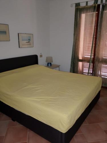 a bed in a room with a yellow bedspread at Villa Paradiso holidays in Costa Paradiso