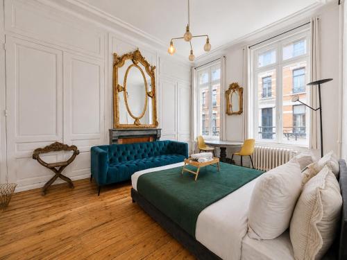 a bedroom with a large bed and a blue couch at Grande Chambre lumineuse Proche Gare et centre ville , métro , Charmante vieille maison Bourgeoise in Tourcoing