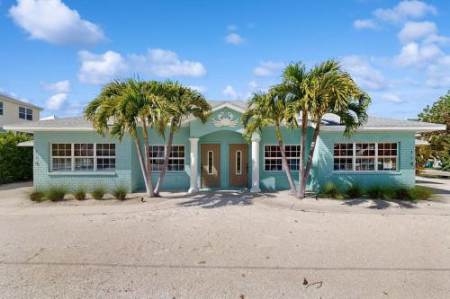 a blue house with palm trees in front of it at King Crab in Holmes Beach