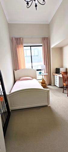 a bedroom with a white bed and a window at The Fifth Season in Unanderra