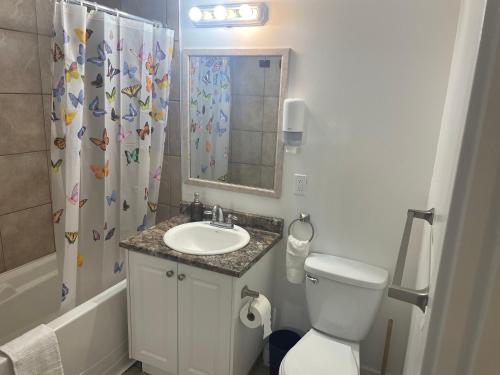 a bathroom with a toilet and a sink and a shower curtain at Bayside Inn in Alert Bay