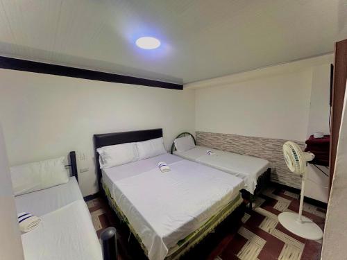 a small room with two beds and a fan at Hotel Bachue Ibagué in Ibagué