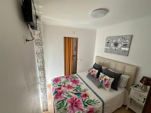 a bedroom with a bed with floral sheets and pillows at Casa Prédio triplex - Faneca Apartamentos in Nazaré