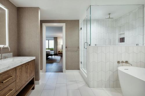 a bathroom with a shower and a tub and a sink at Renaissance Austin Arboretum Domain Hotel in Austin
