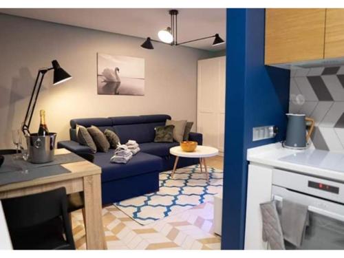a living room with a blue couch and a table at Apartament Augustów SWAN in Augustów