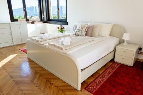 a white bed with towels on it in a room with windows at Entire Villa for 6 near Bled -Private Garden, Grill & Free Parking in Lesce