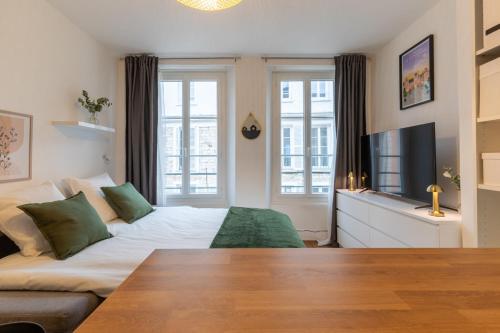 a living room with a bed and a tv at Cœur de Fontainebleau in Fontainebleau