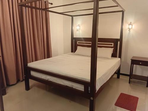 a bedroom with a four poster bed with white sheets at 7C Villa in Galle