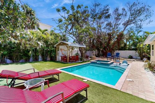 a backyard with a pool with red chairs and a gazebo at Getaway on Gladiolus in Anna Maria