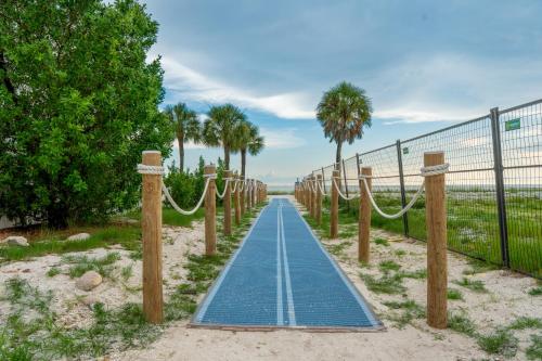 a blue pathway on the beach with trees and a fence at White Cap Condo B201 by Sun Palace Vacations in Fort Myers Beach