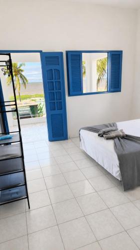 a bedroom with a bed and blue doors and a tiled floor at Casa Estrela Azul in Pitimbu