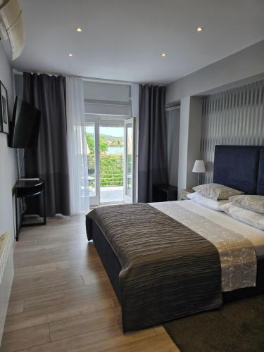 a bedroom with a large bed and a balcony at Apartmani Kameno Sidro in Bilice