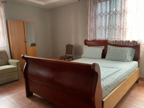 a bedroom with a bed with a chair and a window at ODeTTe GUEST HOUSE in Kumasi