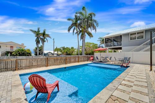 a swimming pool with a red chair and a house at Bungalow B in Bradenton Beach