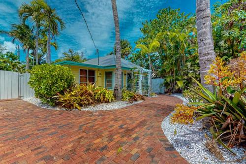 a yellow house with palm trees and a brick driveway at The Wee Cottage in Anna Maria