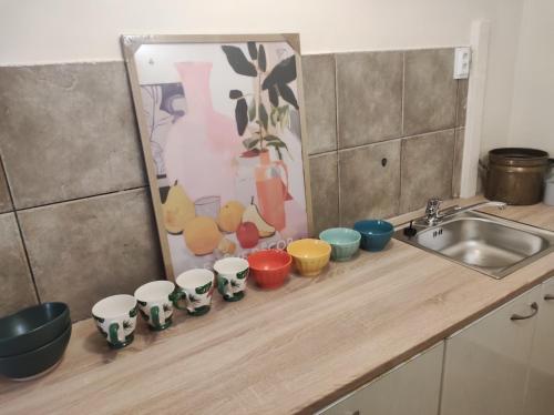 a row of colorful cups sitting on a counter next to a sink at Levendula udvarház in Sopron