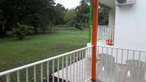two white chairs sitting on a porch of a house at Bungalow PAPAYE in Pointe-Noire