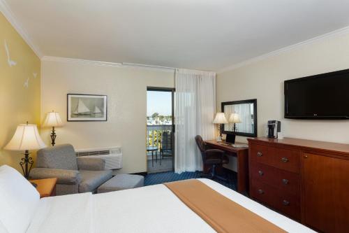 a hotel room with a bed and a desk and a television at The Marina Inn on San Francisco Bay in San Leandro