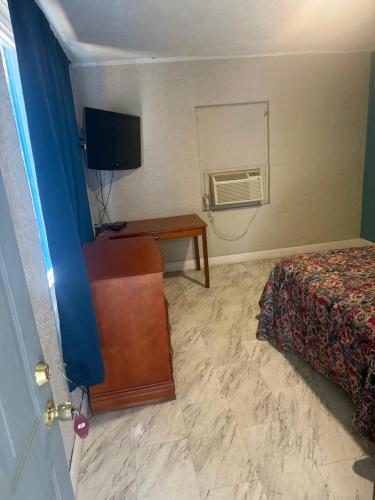 a hotel room with a bed and a desk and a television at Terrace Motel in Natchez