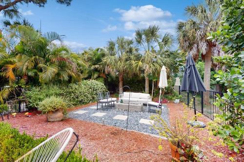 a garden with a patio with an umbrella and chairs at 10 Pines - Sarasota Bay in Sarasota