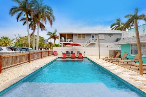 a swimming pool with chairs and a house at Bungalow E in Bradenton Beach