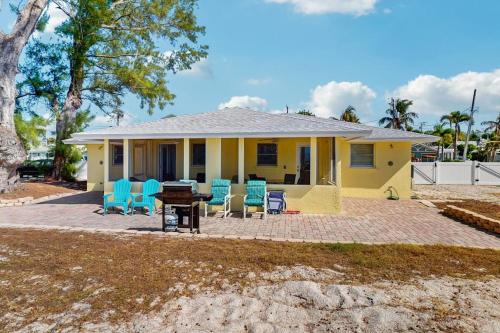 a yellow house with blue chairs and a table at Playa Casanas North in Holmes Beach