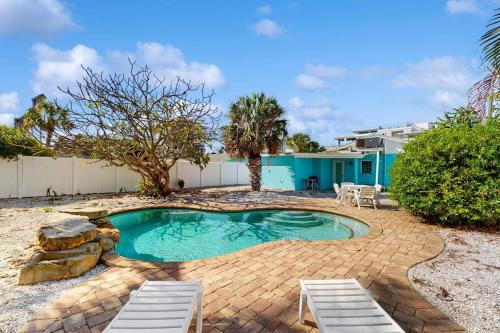 a small swimming pool with two chairs and a house at Sea's The Day in Anna Maria