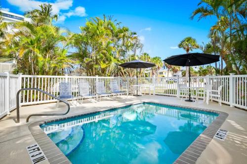 a swimming pool with chairs and umbrellas at Parrot Beach Cottages Suite #2 in Siesta Key
