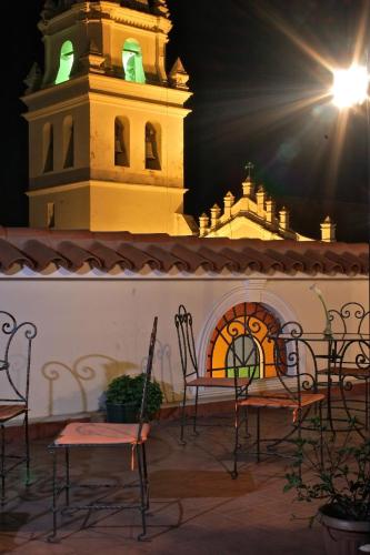 a patio with chairs and a clock tower at night at San Marino Royal Hotel in Sucre