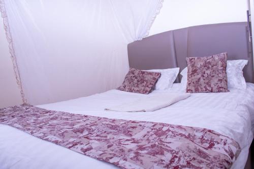 a bed with white sheets and pink pillows at Amber Apartments G1 Kitengela in Athi River