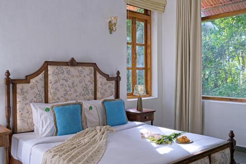 a bedroom with a bed with blue chairs and a window at Villa Eden 3BHK in Assagao