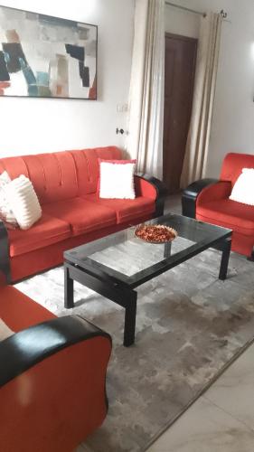 a living room with a red couch and a coffee table at Royal guest home in Bonamoussadi