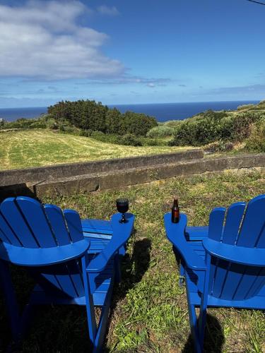 two blue chairs sitting on top of a hill with the ocean at Casa das Brisas Matinais in Conceição
