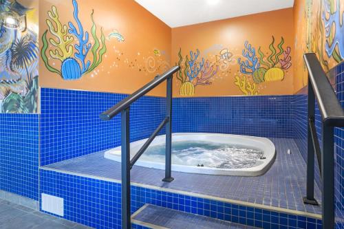 a blue tiled bathroom with a tub in it at Best Western Plus Grand-Sault Hotel & Suites in Grand Falls