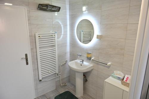 a white bathroom with a sink and a mirror at Modex ROOMS in Paraćin