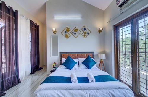 a bedroom with a large bed with blue pillows at TAJ VILLA Mahabaleshwar in Mahabaleshwar