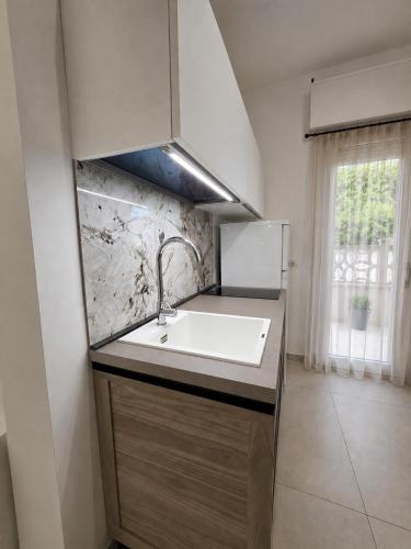 a white kitchen with a sink and a window at Villetta Lu Sule in Porto Cesareo