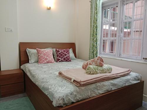 a bedroom with a bed with blankets and a window at Stupas, Temples and Coffee 2BR Flat in Kathmandu in Kathmandu